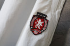 White pants leg with red-and-white crest embroidered patch