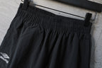 Black elastic-waist pants with pleated front and side logo patch