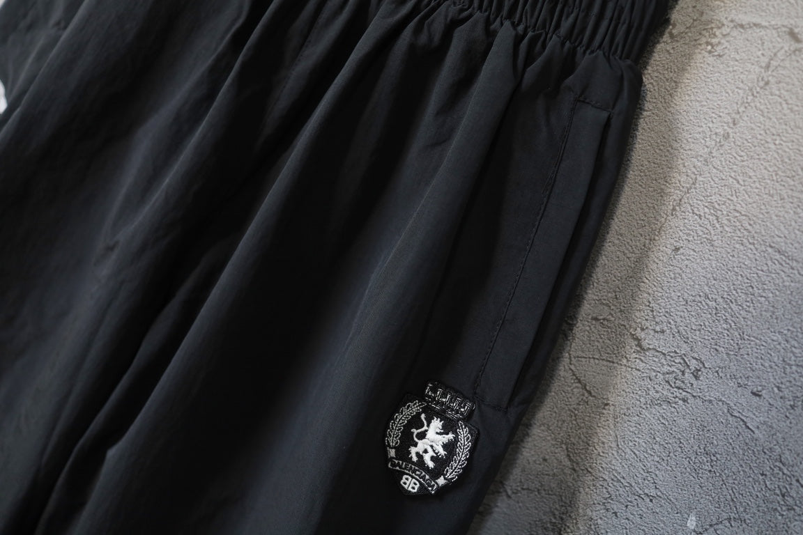 Black wide-leg pants with side crest patch and textured fabric panel