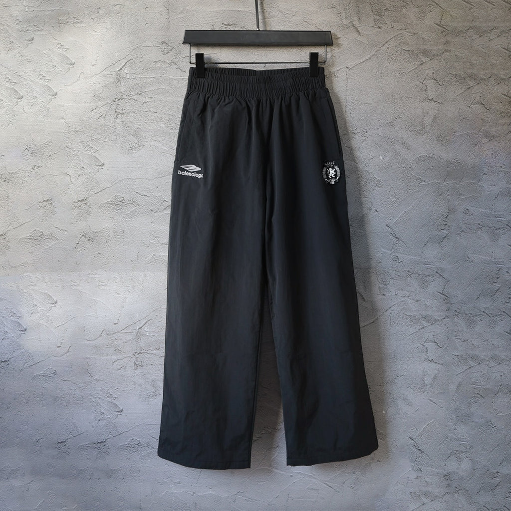 Black Balenciaga wide-leg pants with elastic waistband and side logo patch.