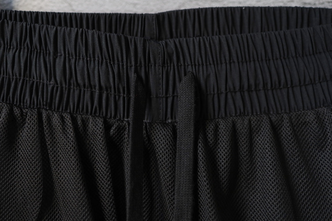 Black elastic waistband pants with stitched panel detailing on the hem
