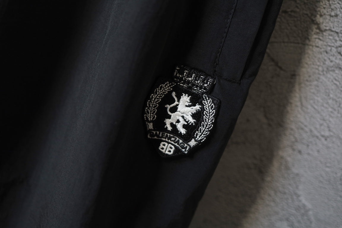 Black pants with embroidered crest logo patch near the side seam
