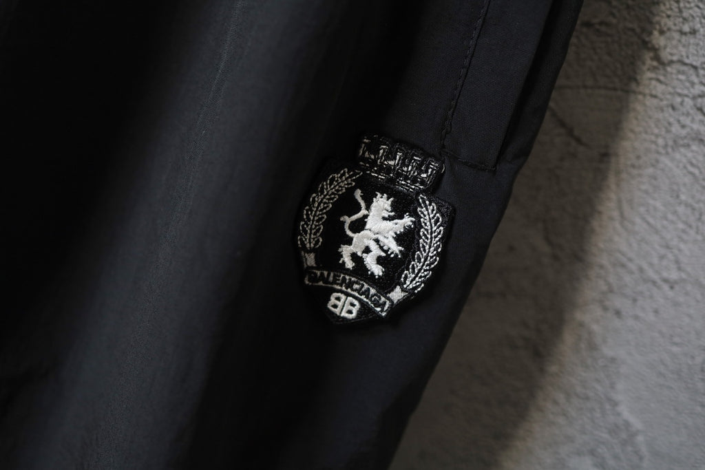 Black Balenciaga crest patch on side of pants near hem.