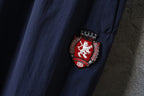 Navy pant leg with red crest patch detail near the hem