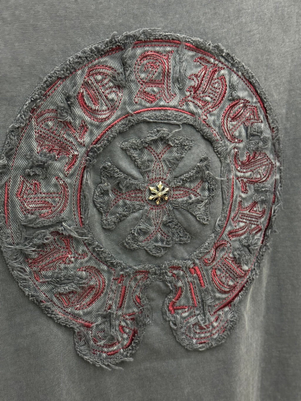 Close-up of ornate circular embroidery with red thread accents and gold-tone center