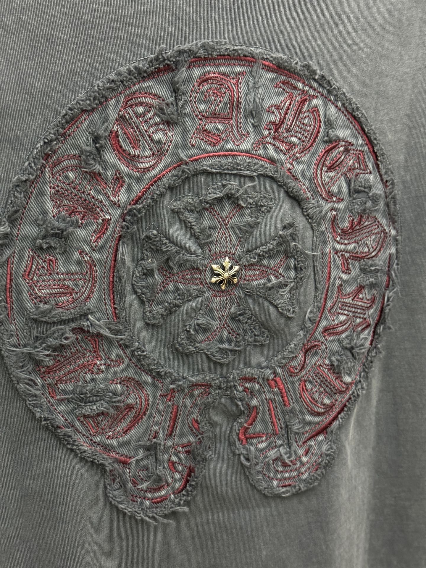 Close-up of ornate circular embroidery with red thread accents and gold-tone center