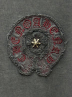 Embroidered circular patch with textured gray stitching and gold-tone center emblem