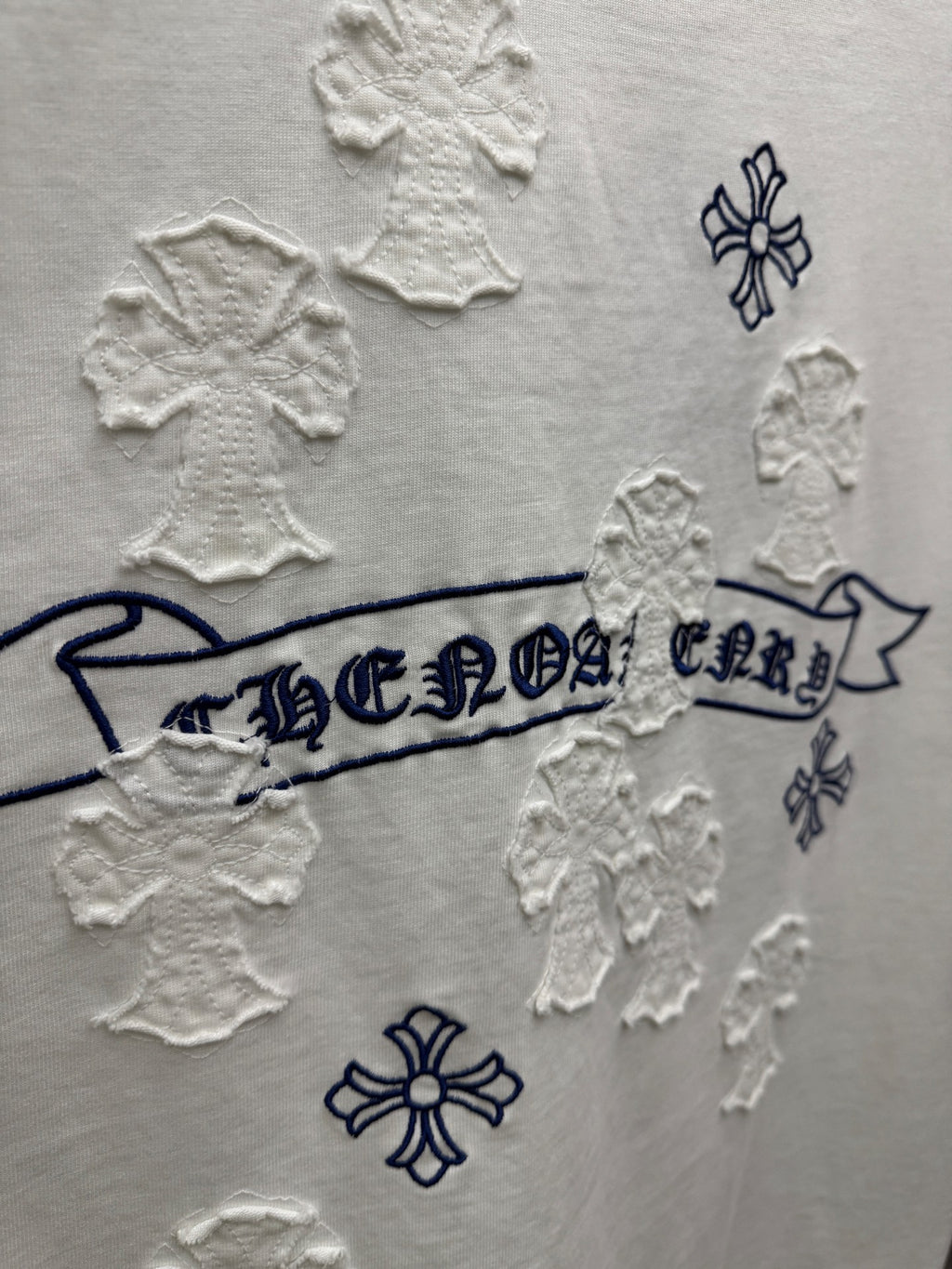 White short-sleeve T-shirt close-up of back banner text surrounded by raised snowflake patches