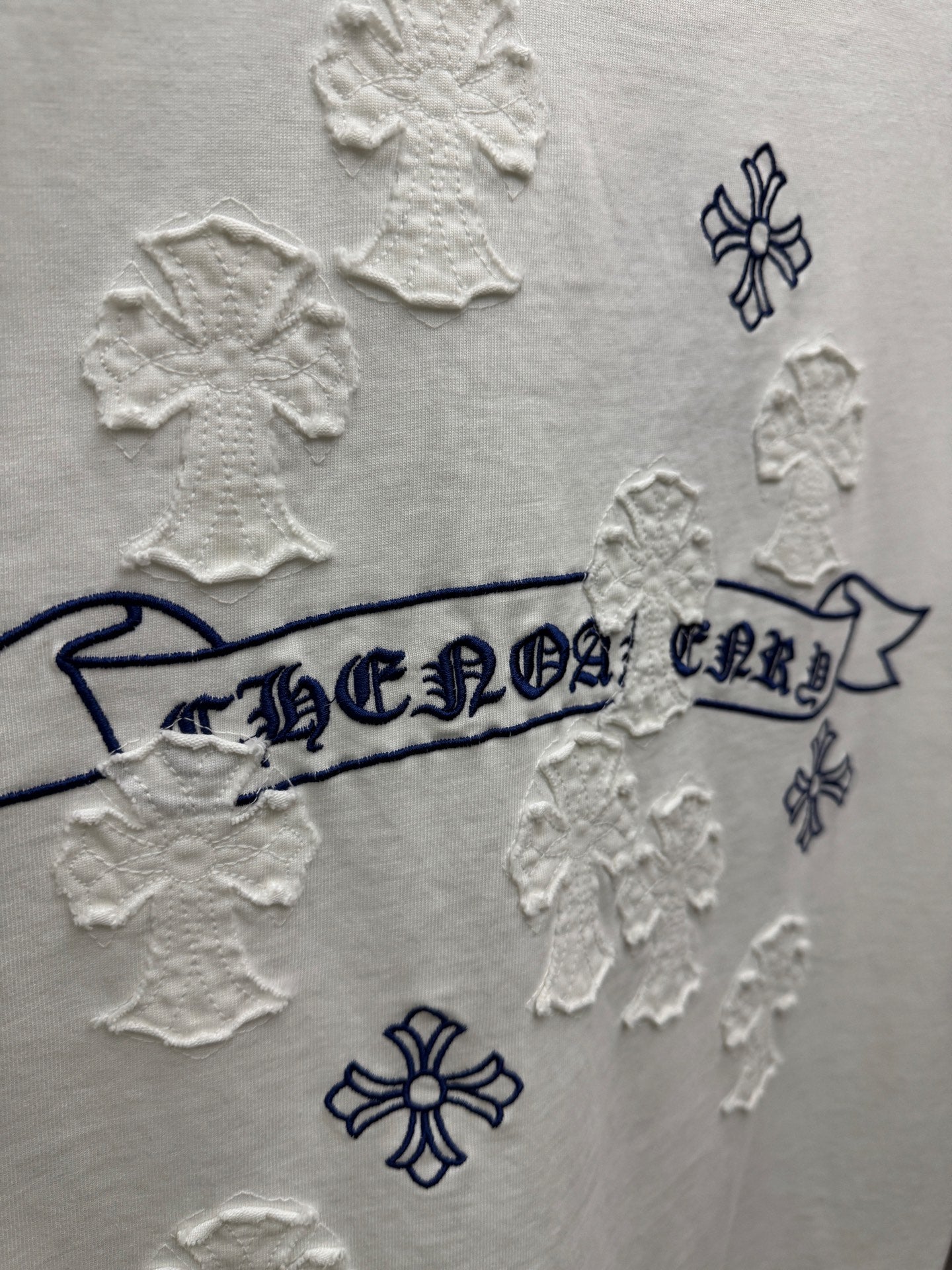 White short-sleeve T-shirt close-up of back banner text surrounded by raised snowflake patches