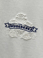 White short-sleeve T-shirt close-up of blue banner text with raised stitched snowflake texture
