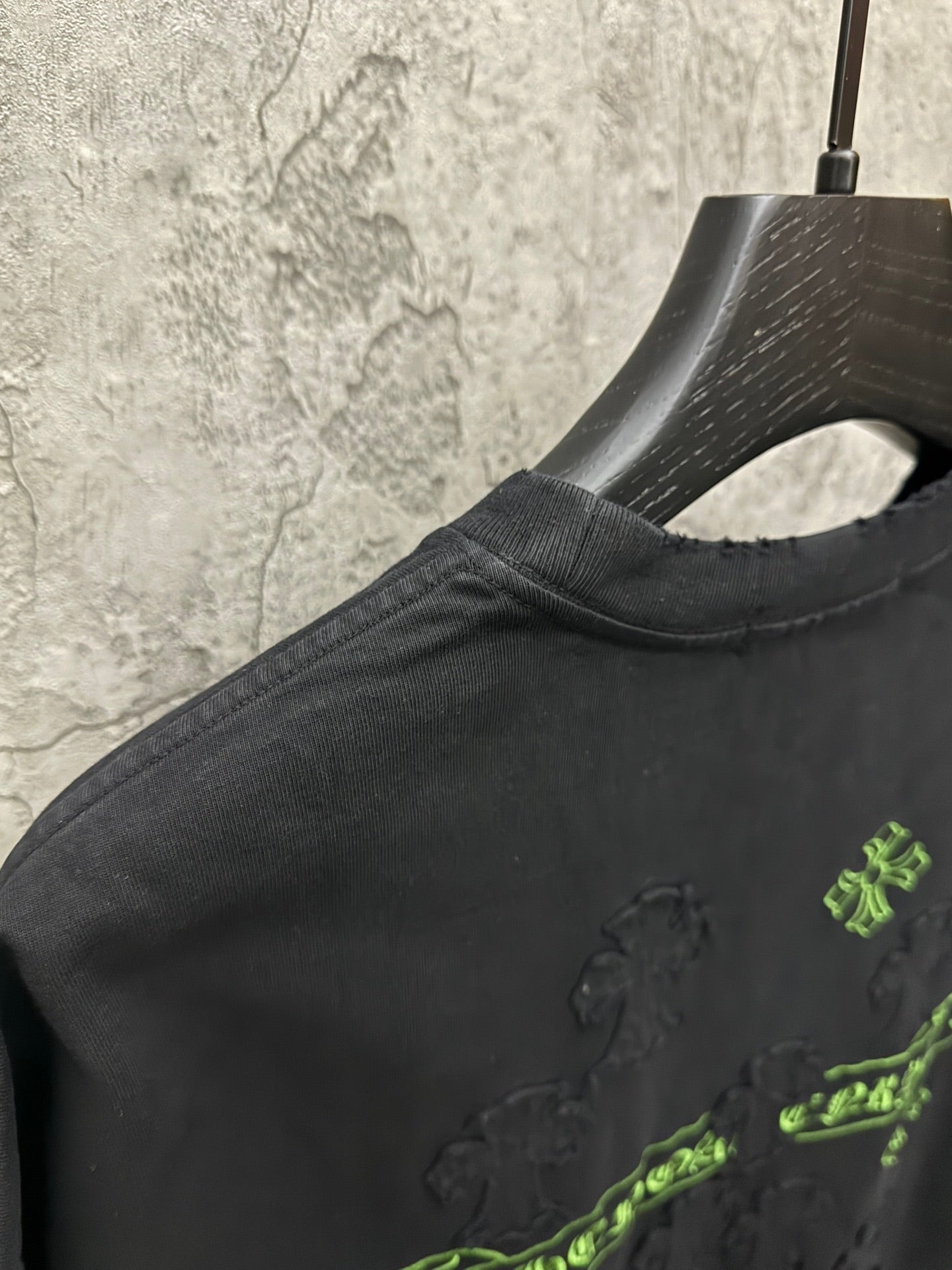 Black short-sleeve T-shirt close-up of shoulder and green embroidered emblem
