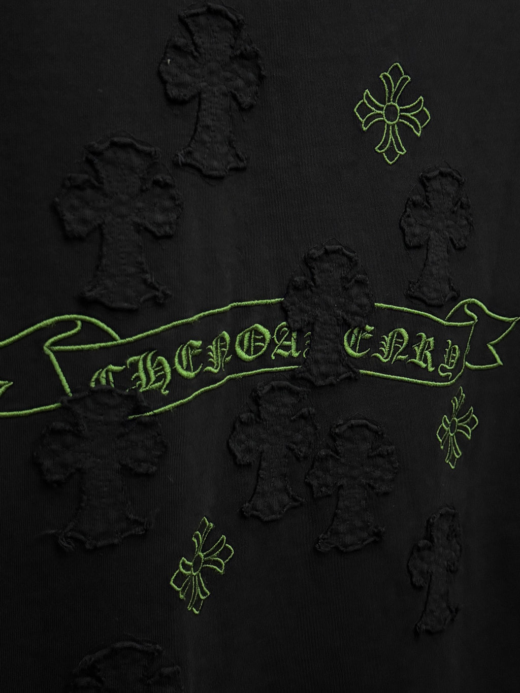 Black short-sleeve T-shirt close-up of green embroidered banner and cross motifs