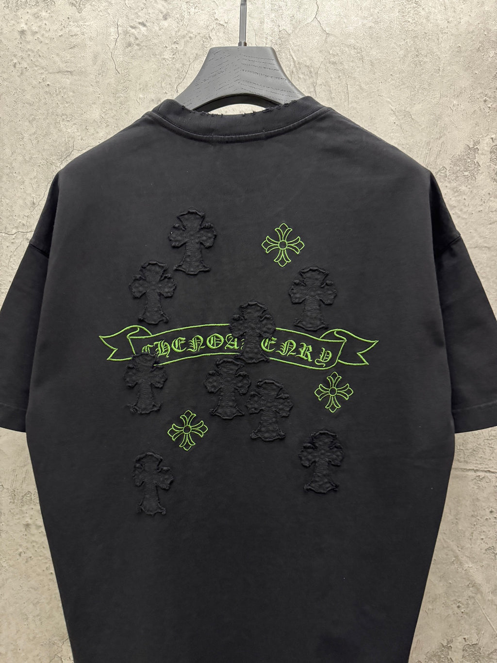 Black short-sleeve T-shirt back view with green banner and clover cross icons