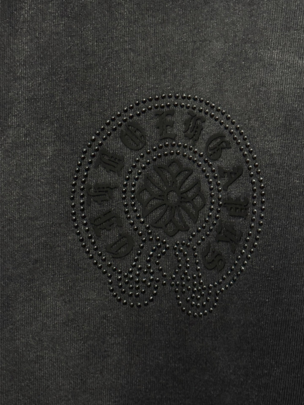 Dark gray T-shirt fabric with circular rhinestone skull emblem detail