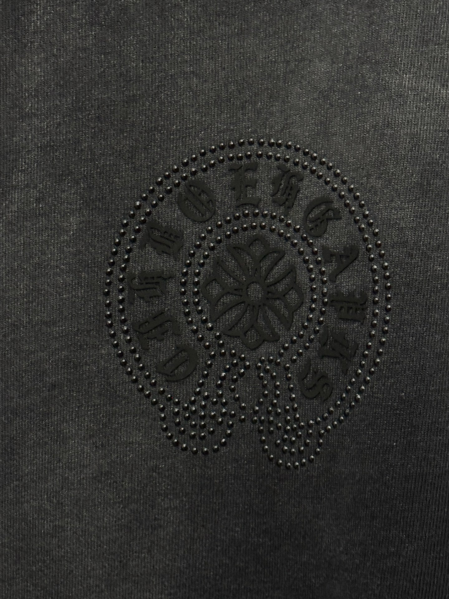 Dark gray T-shirt fabric with circular rhinestone skull emblem detail