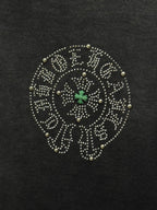 Round studded emblem detail on dark T-shirt with small green star center