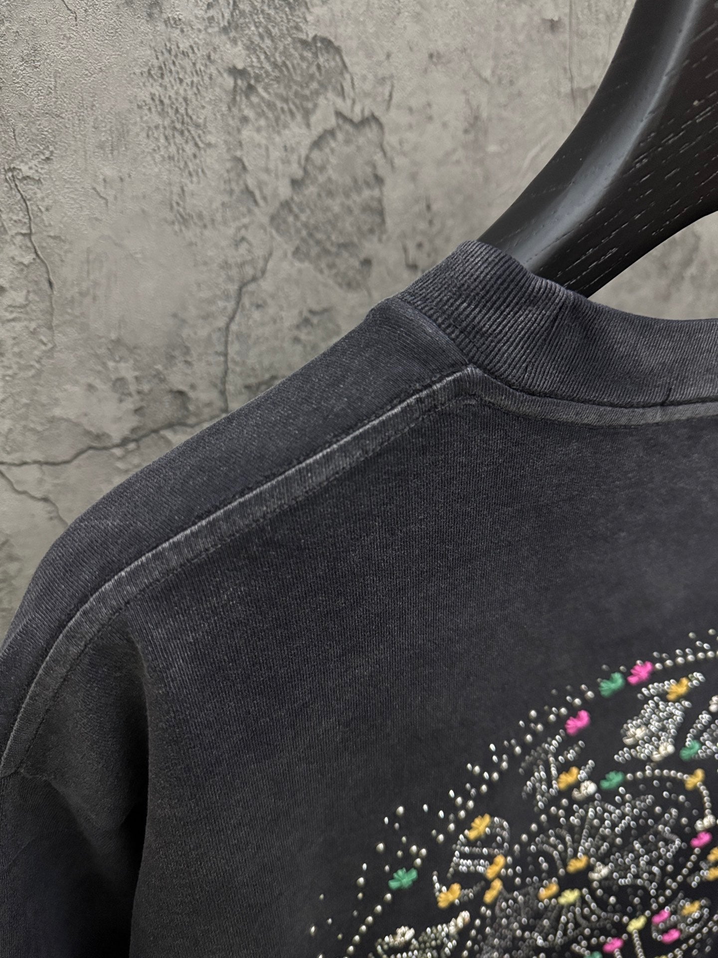 Dark short-sleeve T-shirt shoulder seam with partial studded circular graphic