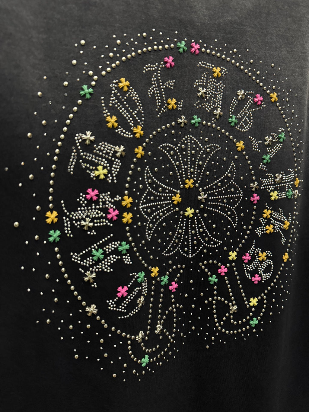 Close-up of studded circular back graphic with colorful accents on dark T-shirt