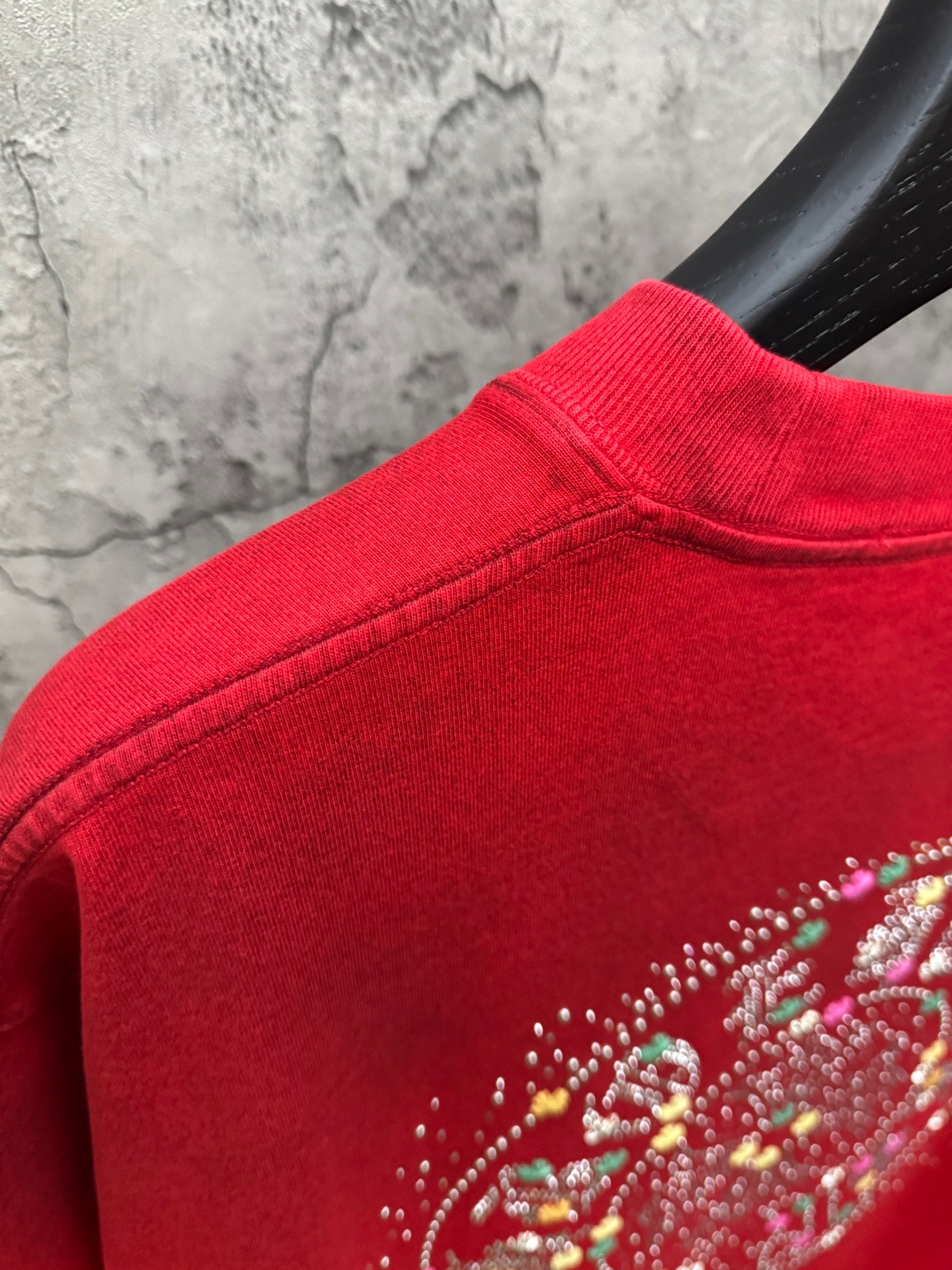Red T-shirt with studded rhinestone design near shoulder seam