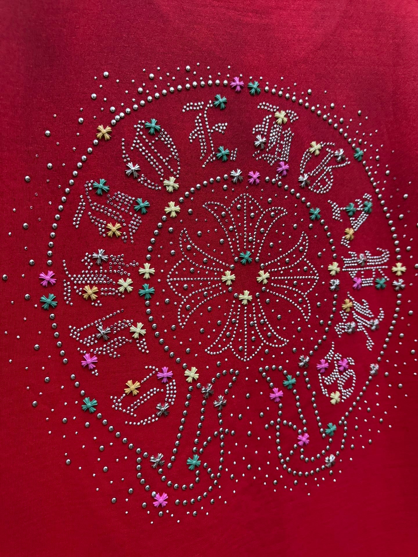 Red T-shirt with close-up of large circular rhinestone pattern and multicolor accents