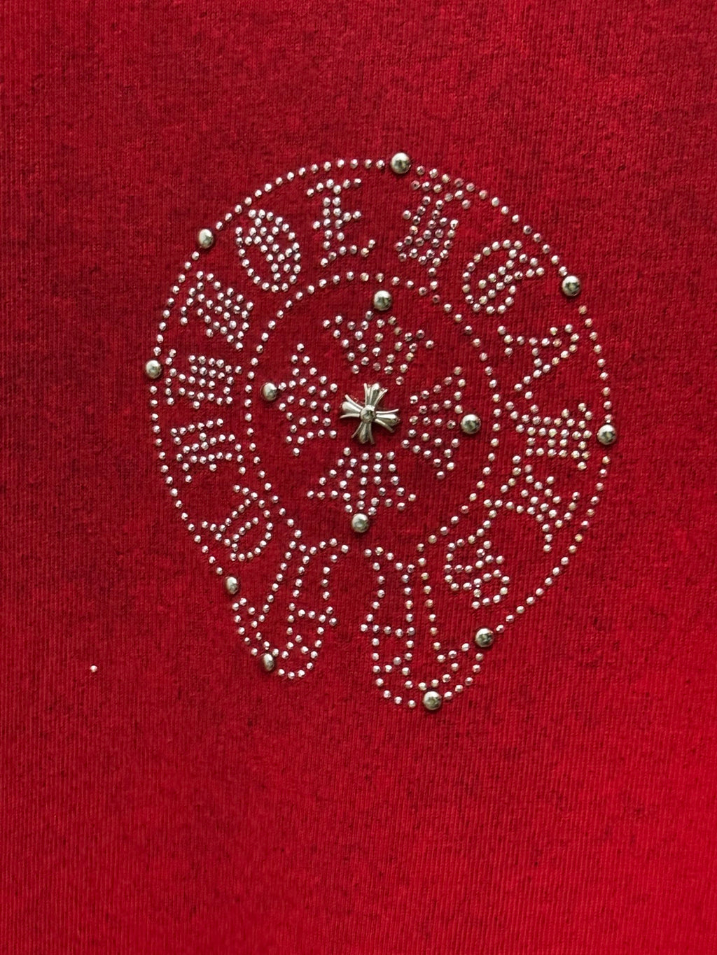 Red T-shirt with close-up of circular rhinestone logo with green and gold accents