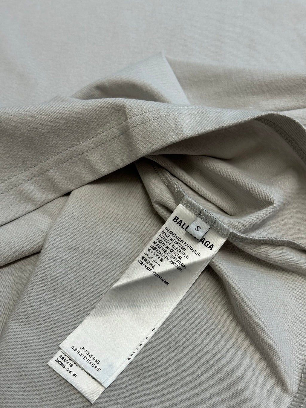 Light gray T-shirt folded with visible care and label tags