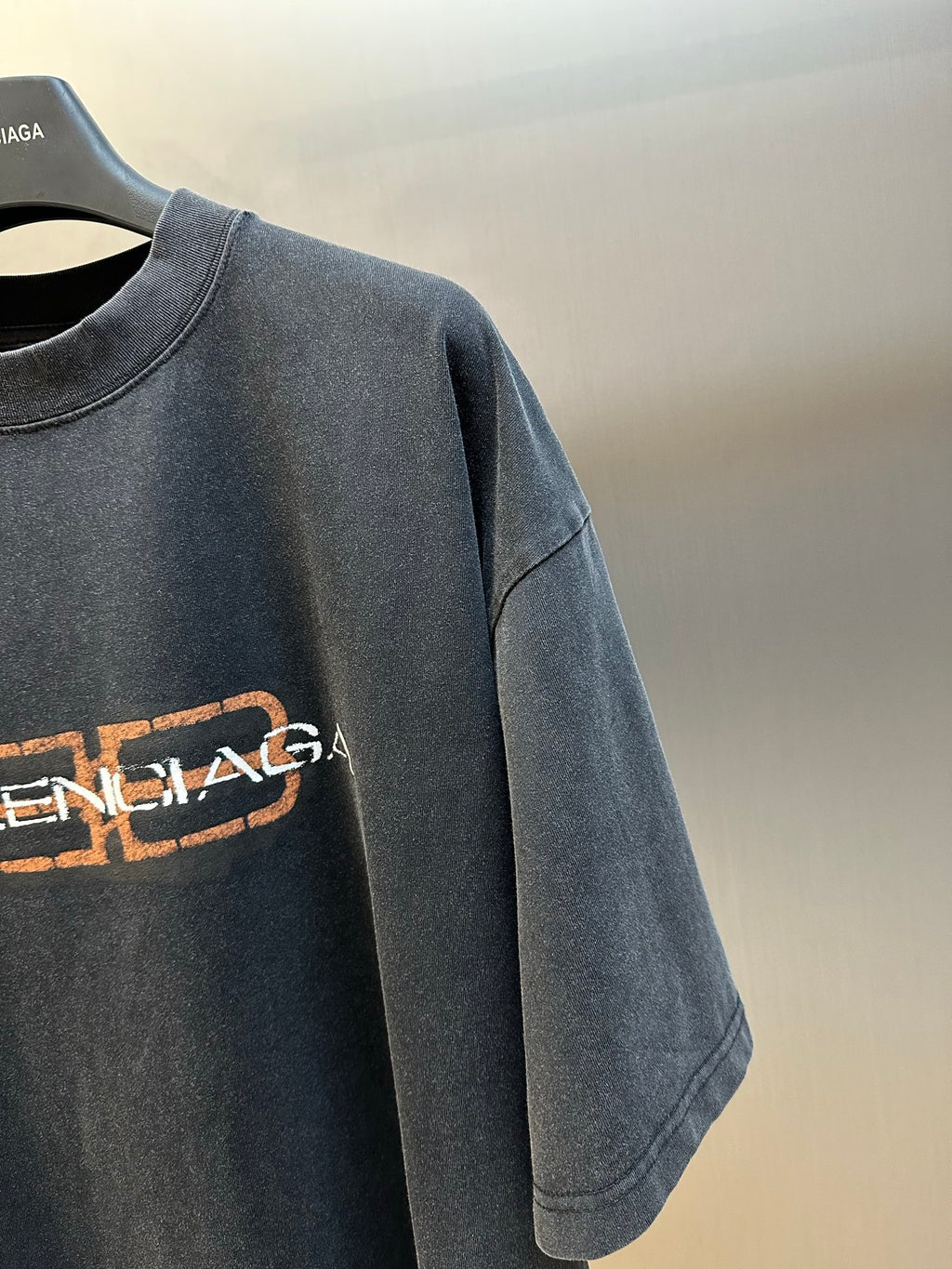 Balenciaga logo T-shirt sleeve and chest detail, dark gray with orange-and-white print