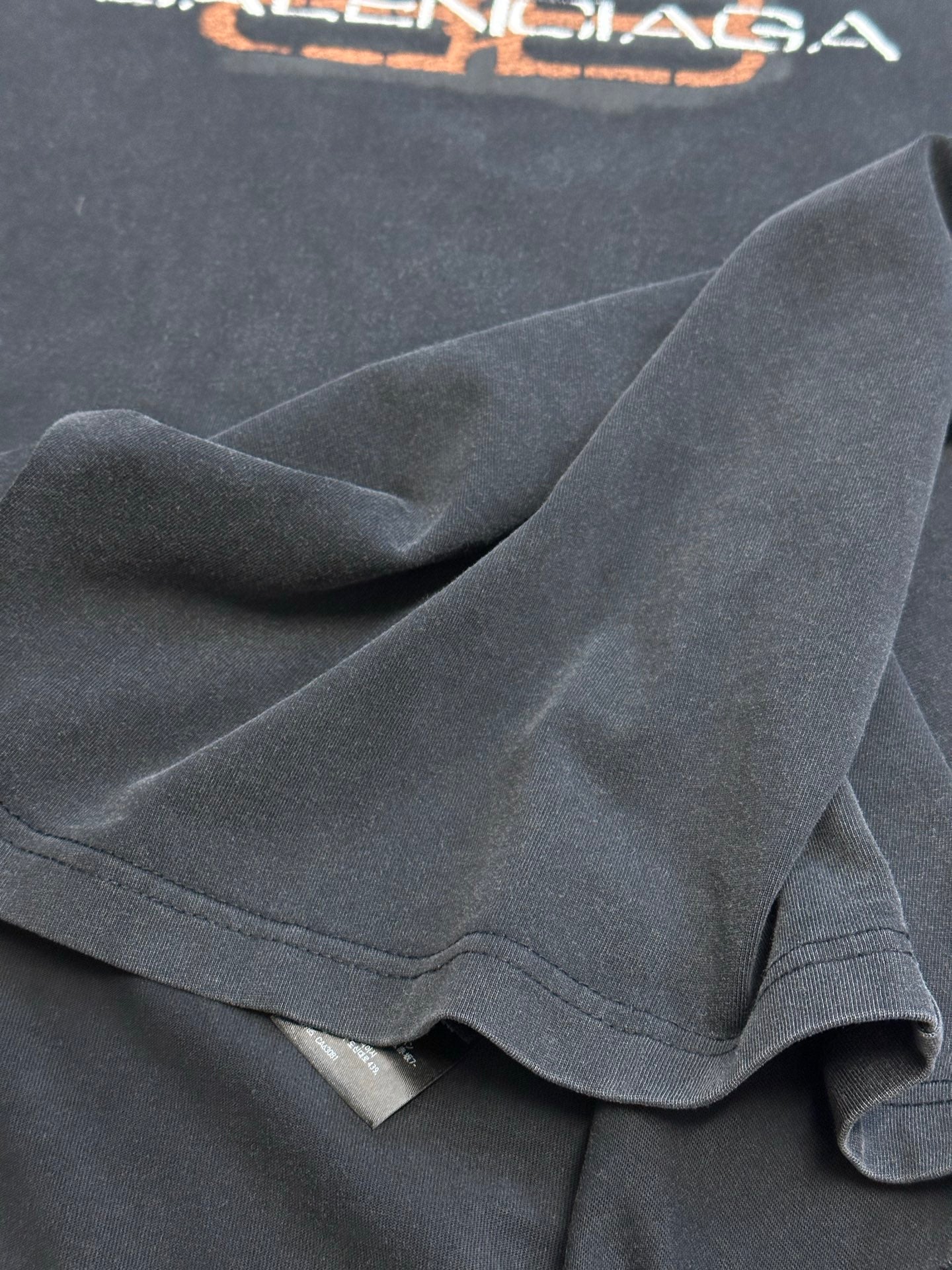 Dark gray Balenciaga T-shirt fabric close-up showing knit texture and sleeve hem