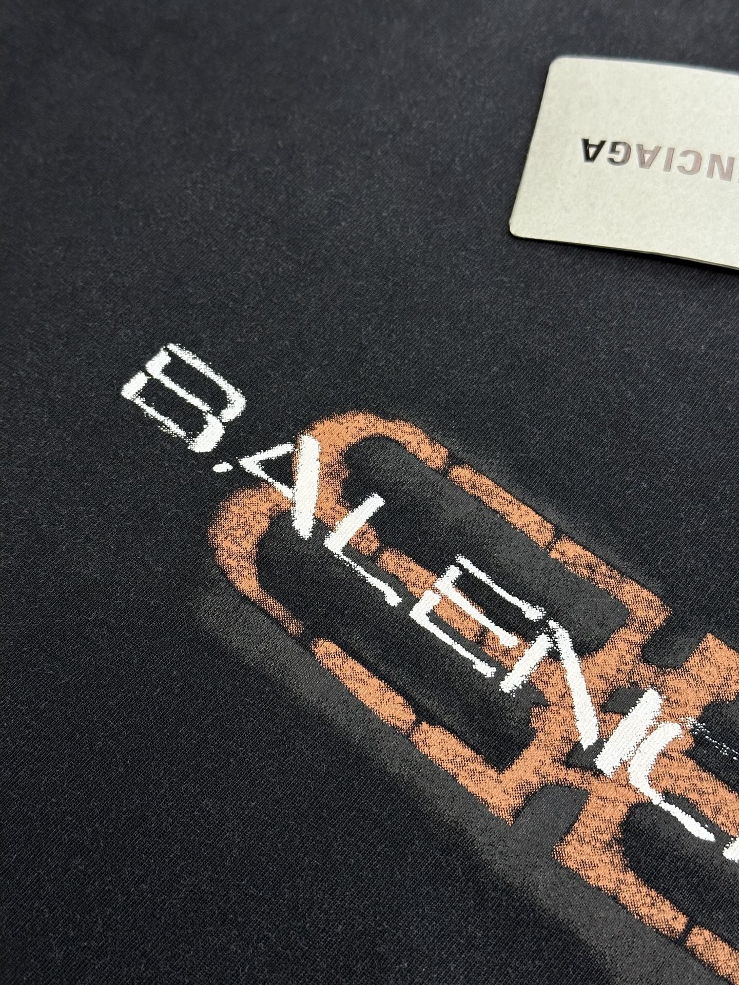 Balenciaga logo close-up on dark gray T-shirt with orange-and-white print