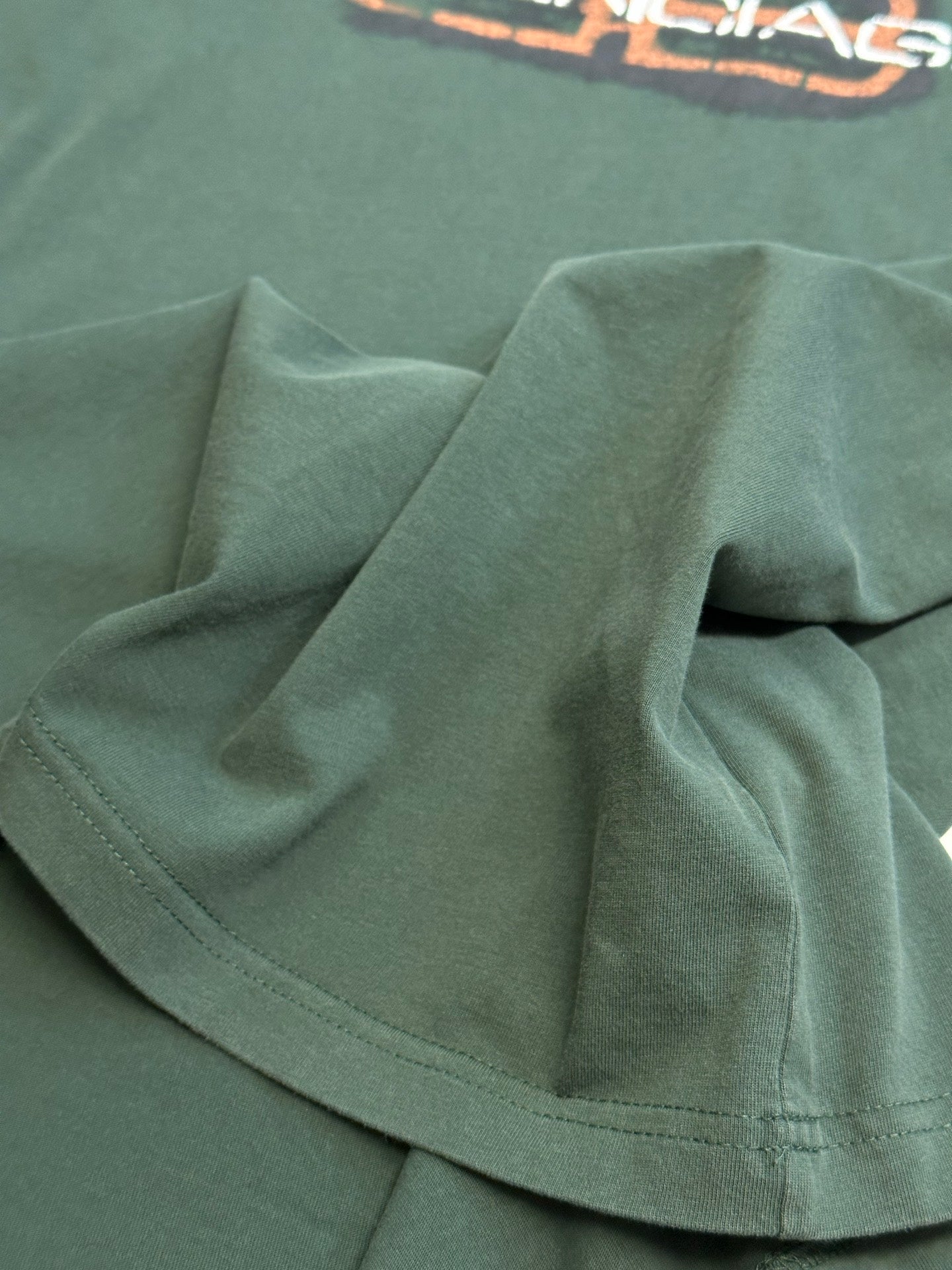 Balenciaga short-sleeve T-shirt fabric close-up in dark green with stitched hem