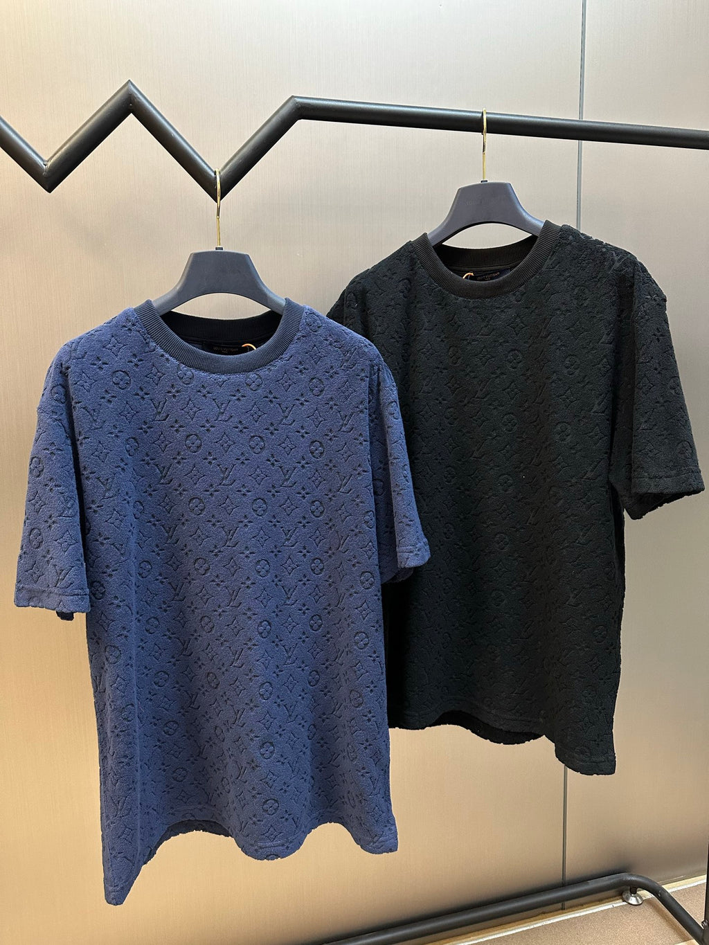 Two short-sleeve crewneck T-shirts on hangers: blue and dark navy monogram