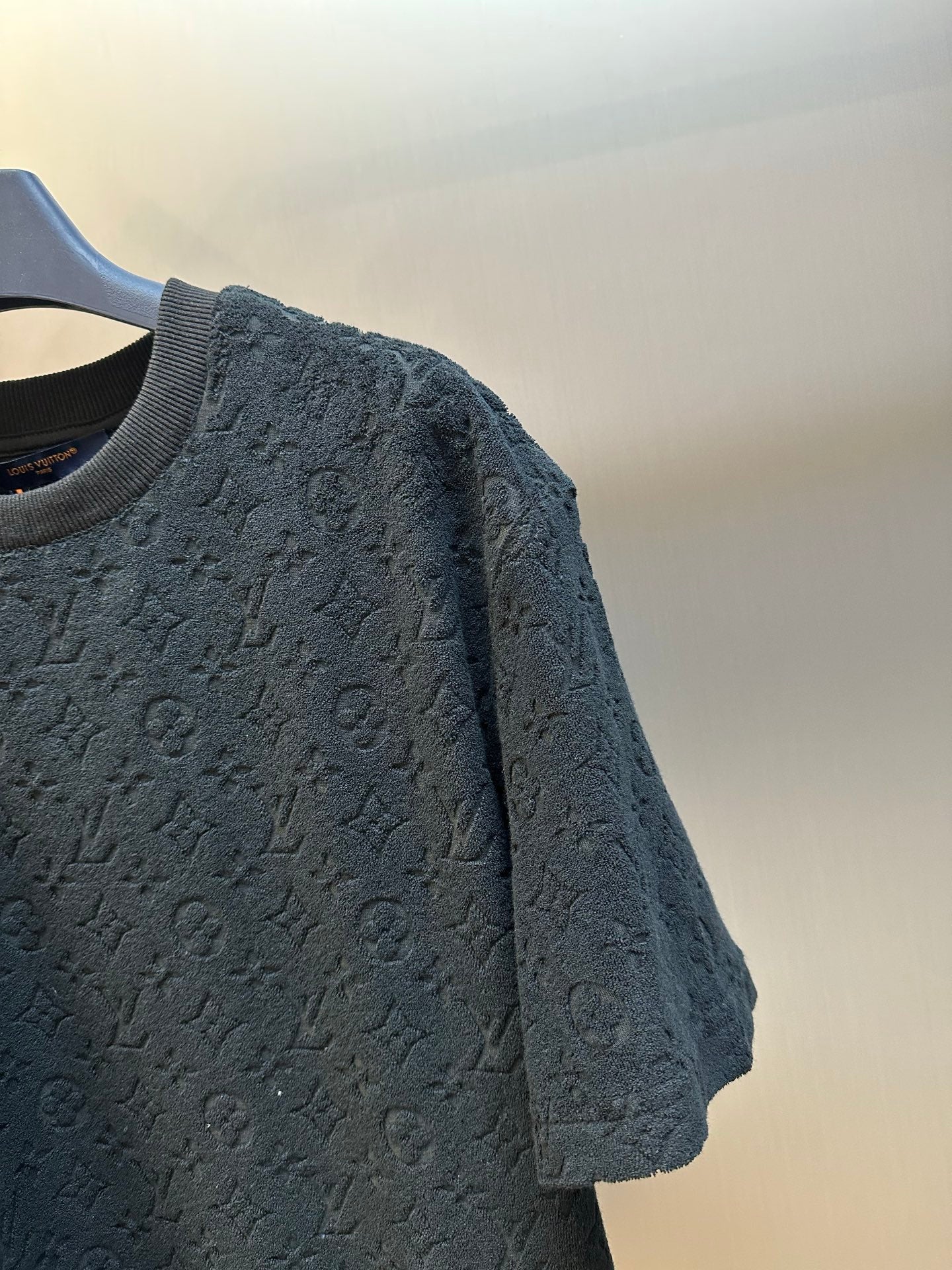 Close-up of navy short-sleeve crewneck T-shirt with allover monogram pattern