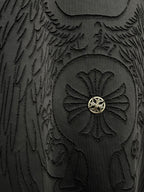 Close-up of embossed winged emblem with gold center on dark t-shirt