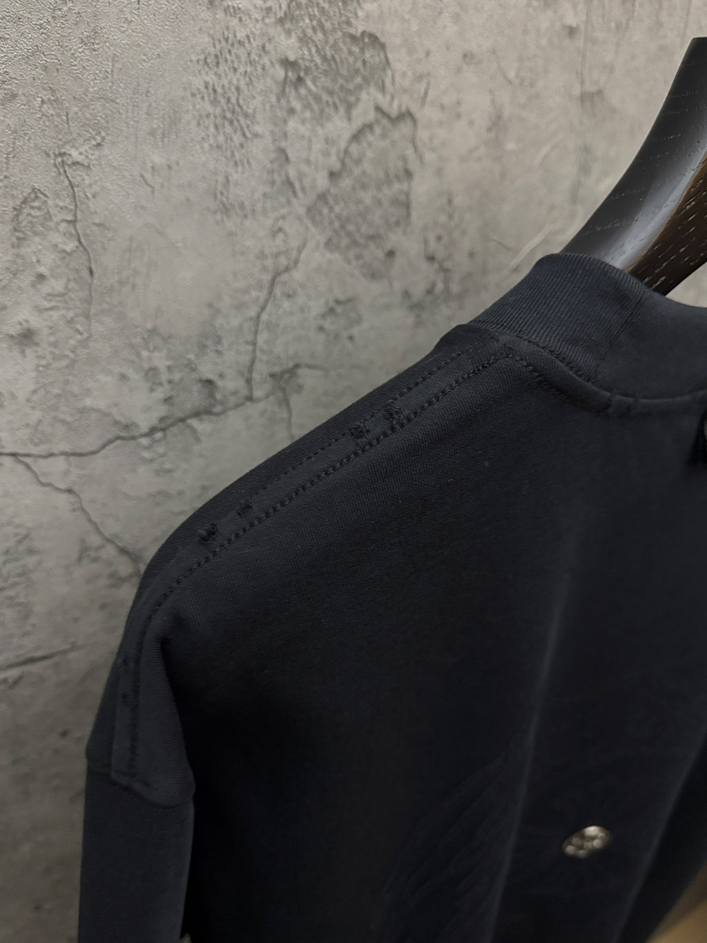 Dark short-sleeve t-shirt shoulder seam with small gold detail