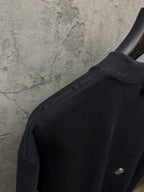 Dark short-sleeve t-shirt shoulder seam with small gold detail
