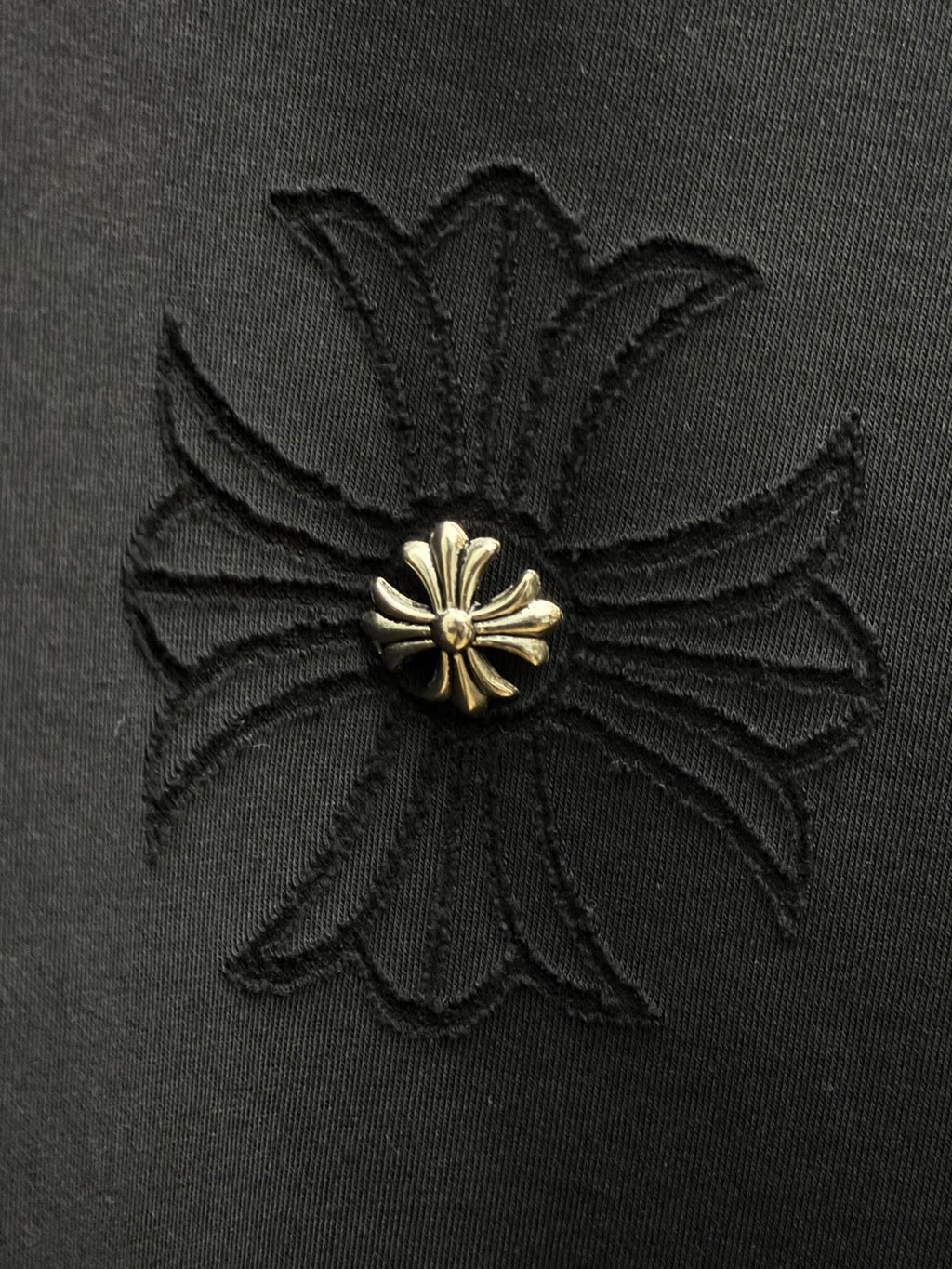 Embroidered flower-like gold emblem on dark fabric