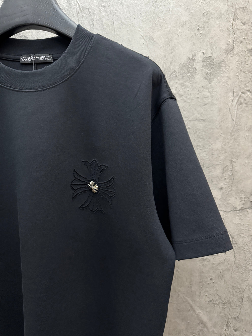 Dark short-sleeve t-shirt with small chest emblem and visible sleeve