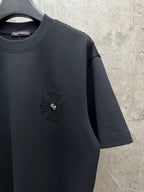 Dark short-sleeve t-shirt with small chest emblem and visible sleeve