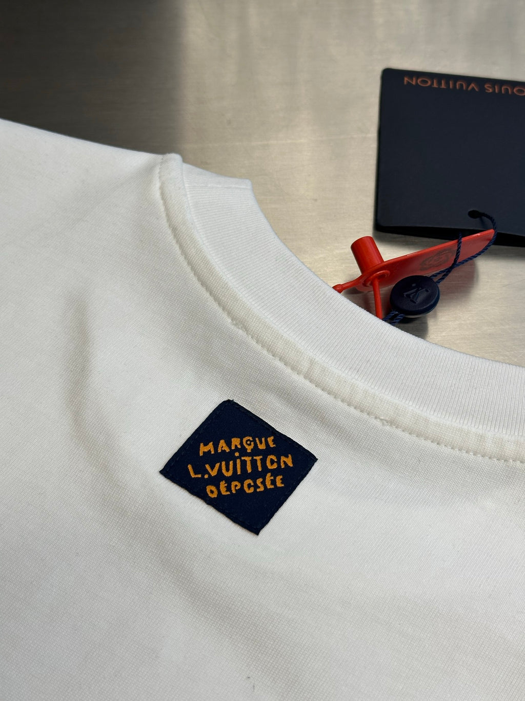 White T-shirt with multicolor logo label near collar and blue trim
