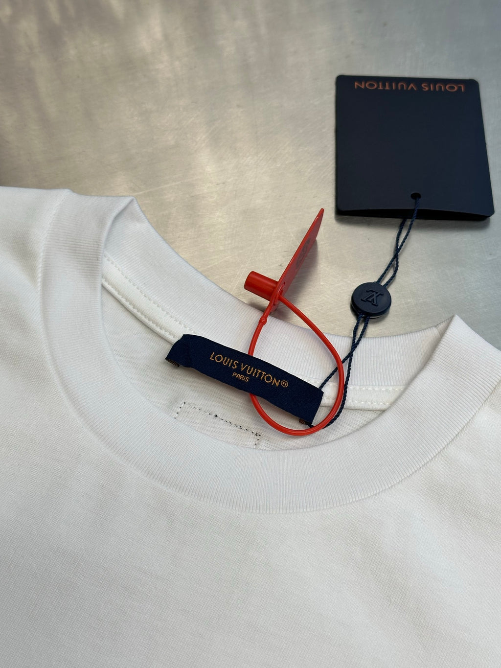 White T-shirt neckline with Louis Vuitton tag and red/blue security label