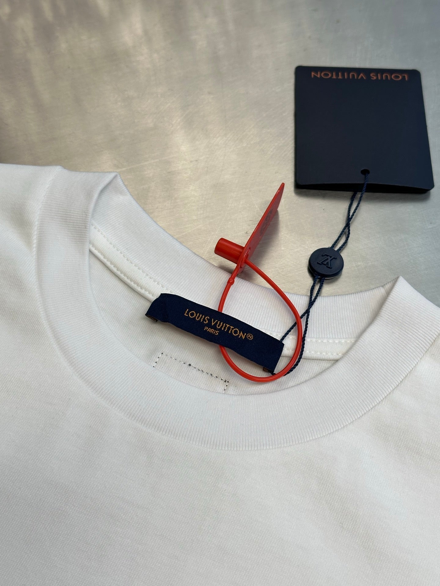 White T-shirt neckline with Louis Vuitton tag and red/blue security label