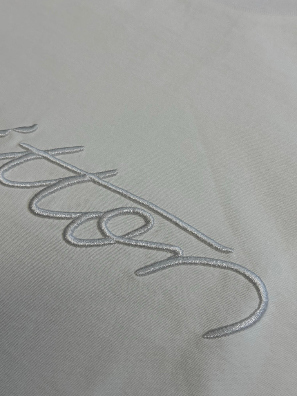 White fabric with Louis Vuitton signature-style embroidery close-up