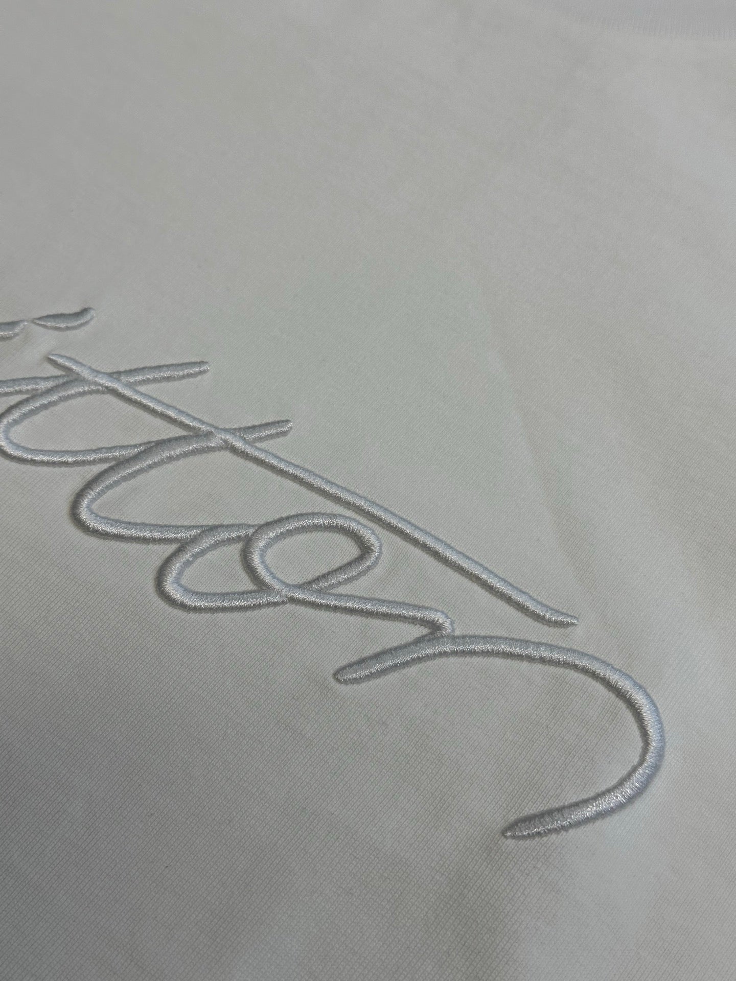 White fabric with Louis Vuitton signature-style embroidery close-up