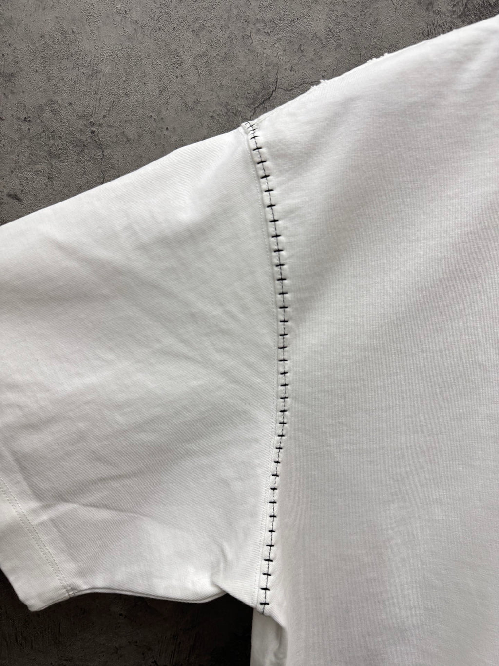 White short-sleeve T-shirt sleeve showing close-up stitched edge