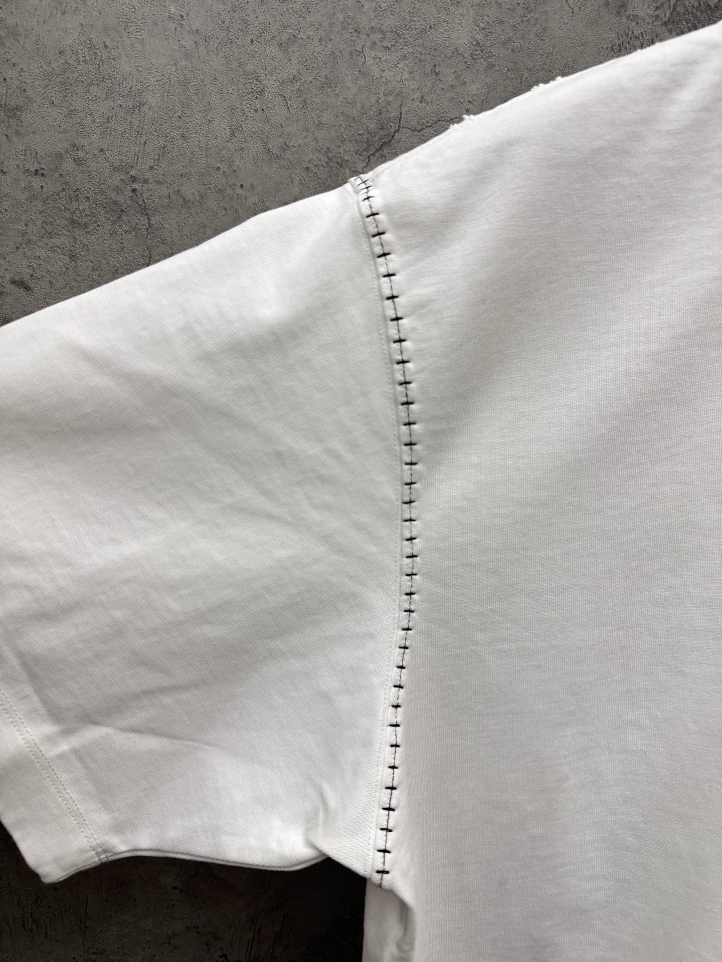 White short-sleeve T-shirt sleeve showing close-up stitched edge