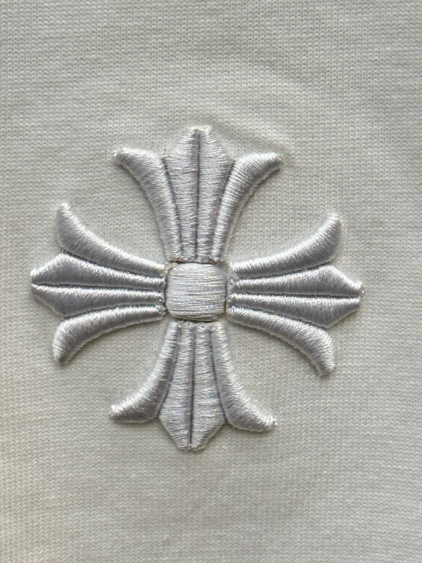 Embroidered silver flower emblem on white short-sleeve T-shirt