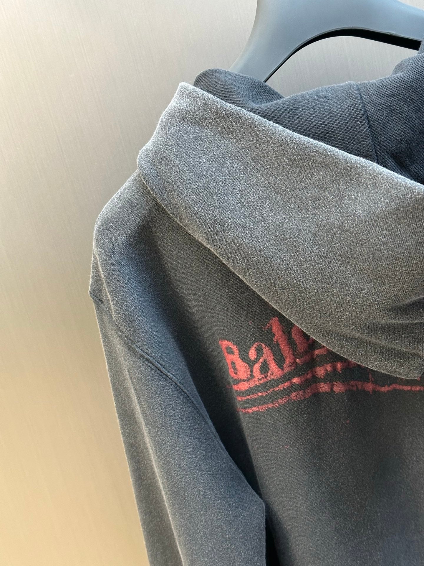 Dark gray hoodie sleeve with red printed logo on upper arm