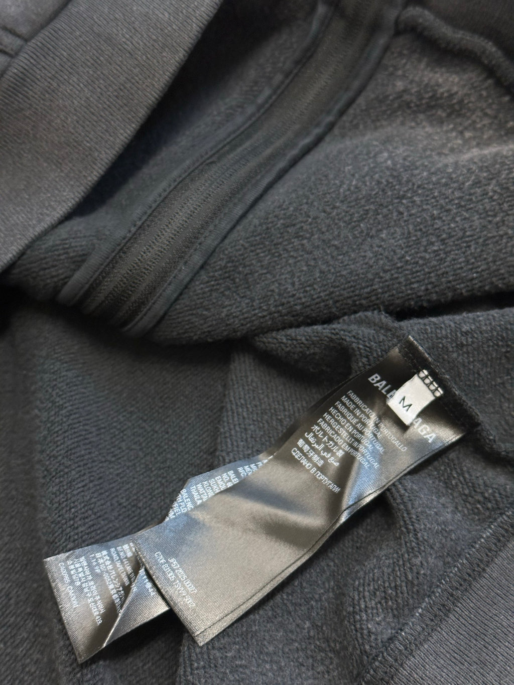 Dark gray hoodie zipper with care and size label inside hem