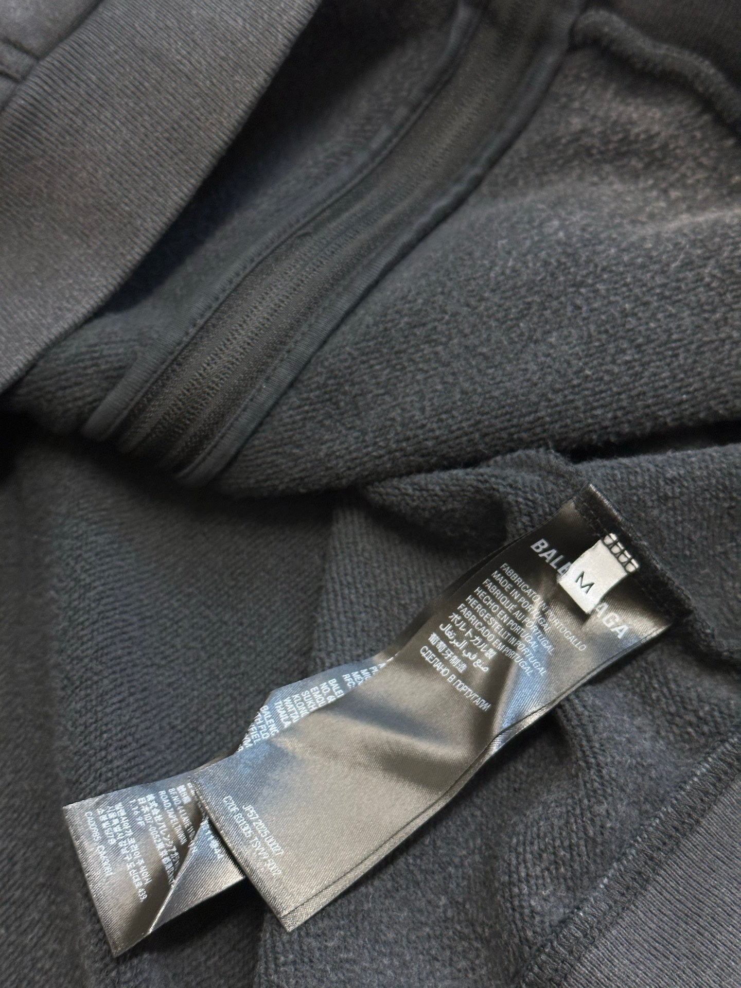 Dark gray hoodie zipper with care and size label inside hem