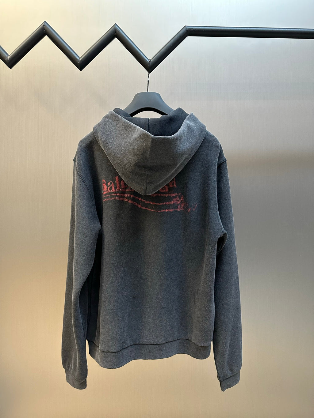 Dark gray zip hoodie with hood and red arched logo graphic on back